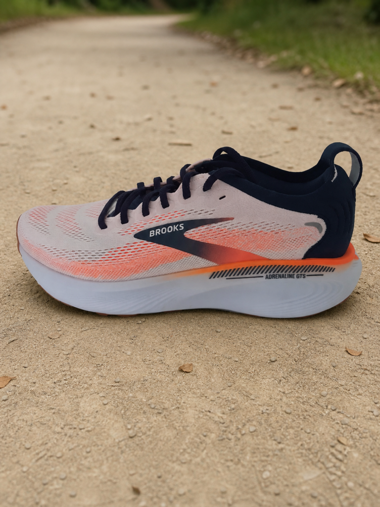 Brooks Adrenaline GTS 25 homme corail et bleu marine sur un chemin stabilisé de parc