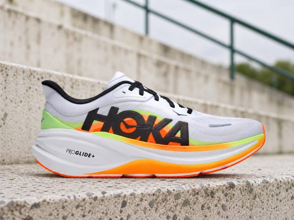 HOKA Clifton Pro blanche orange et verte sur des gradins en terrazzo