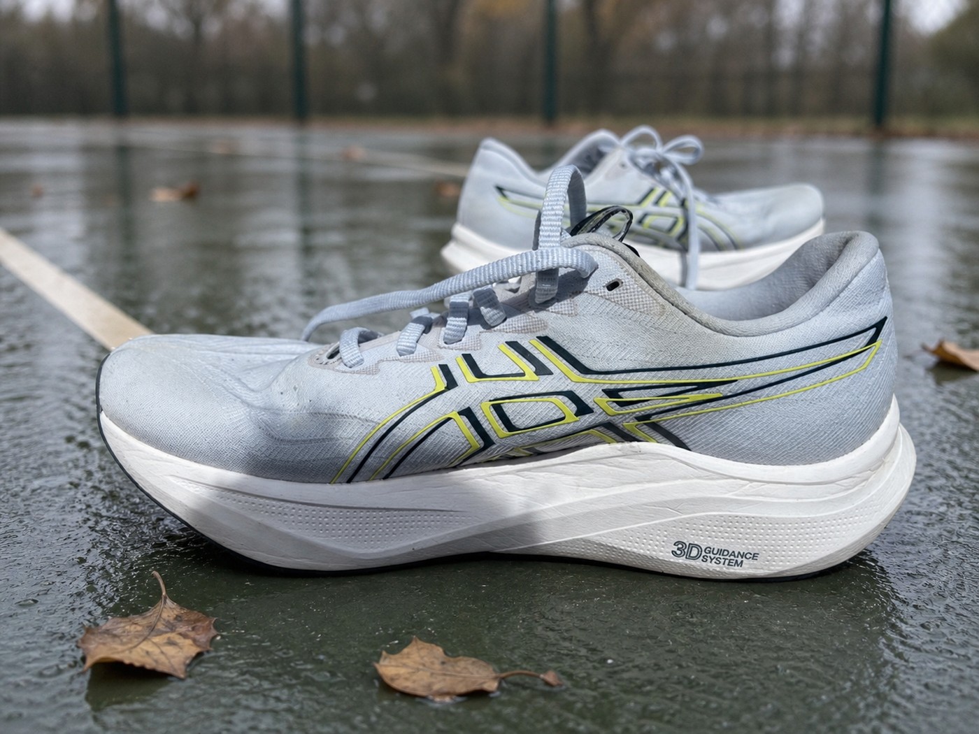 Profil des ASICS GT-2000 14 grises sur un court humide