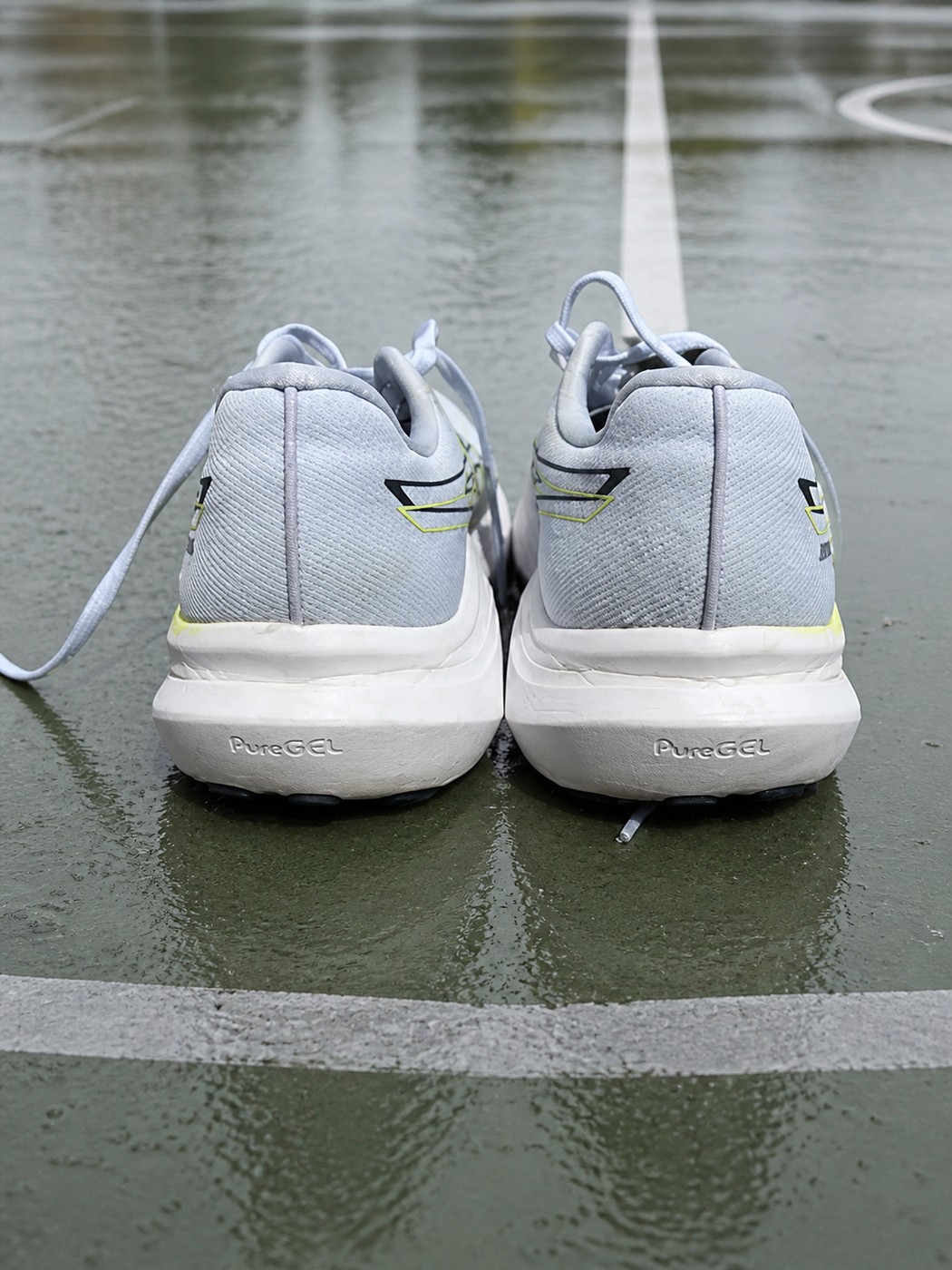 Vue arrière des ASICS GT-2000 14 sur un terrain de sport mouillé