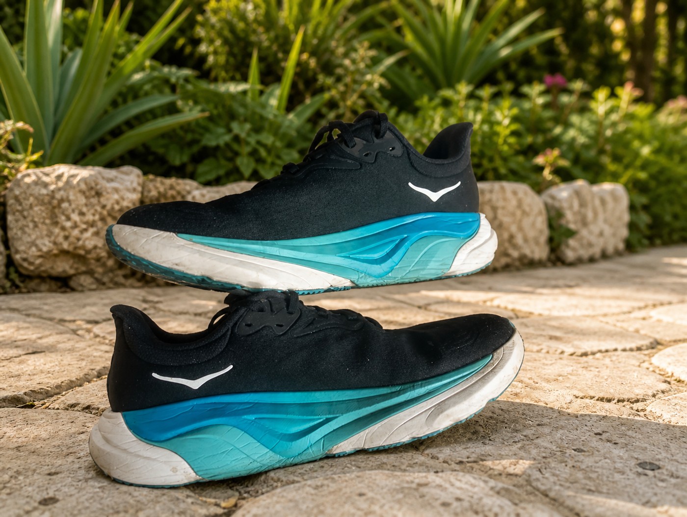 Profil des HOKA Arahi 8 noires sur des dalles de jardin