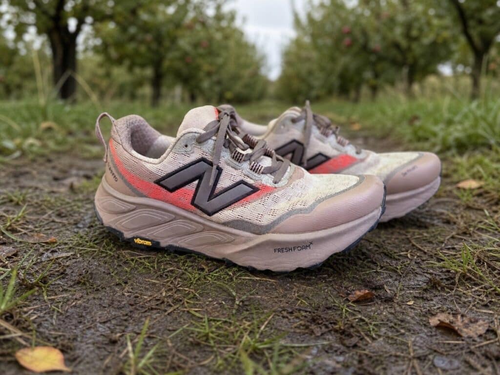 New Balance Fresh Foam X Hierro v9 homme beige et corail sur un chemin humide dans un verger